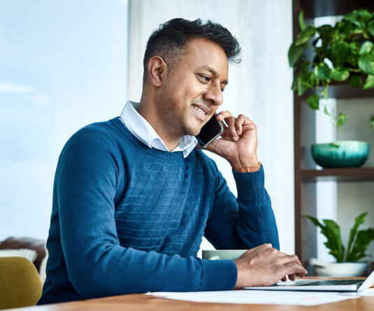 Man talking on a smartphone and using a laptop