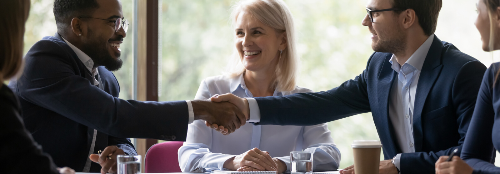 A group of businesspeople in a meeting, two are shaking hands