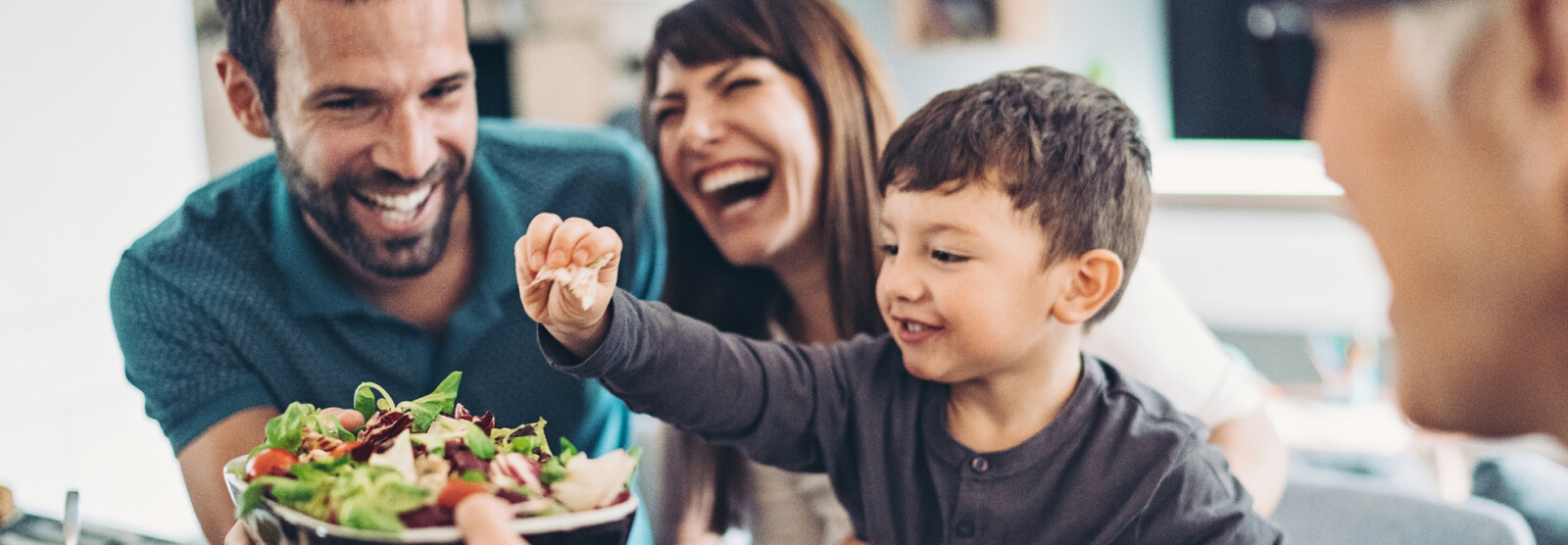 A young family laughing over dinner